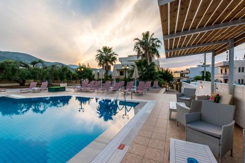 a pool at a hotel with chairs at Newcastle Studios by Estia in Malia