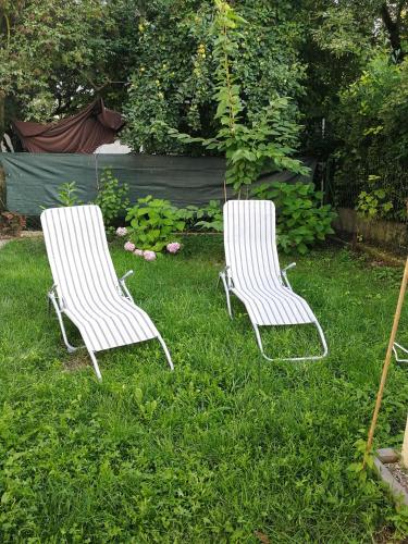 Zwei weiße Stühle stehen im Gras in einem Garten. in der Unterkunft The Place in Ljubljana