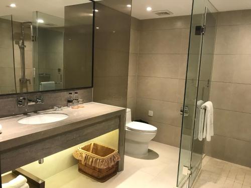 a bathroom with a sink and a toilet and a glass shower at Zhongshan International Hotel in Zhongshan