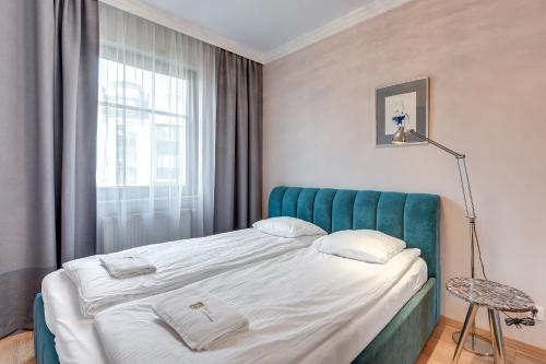 a bedroom with a bed with a blue headboard and a window at Sopocka Bryza - Baltica Apartments in Sopot