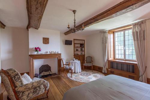 a bedroom with a bed and a fireplace and a table at Les Goubelins in La Lande-dʼAirou