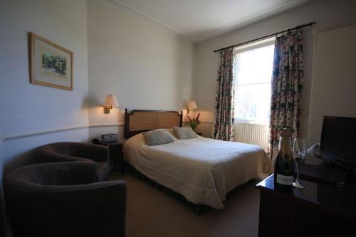 a bedroom with a bed and a chair and a television at Worsley Arms Hotel in Hovingham