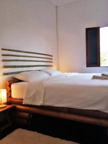 a bedroom with a large white bed with a window at Vanpila in Savannakhet