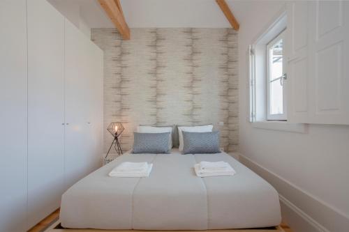 a bedroom with a large white bed with blue pillows at Liiiving in Porto | Historic & Sunny Terrace in Porto