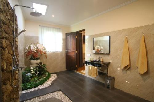 a bathroom with a shower with a sink and a mirror at Villa Capung Mas Ubud in Ubud