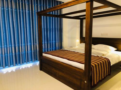 a bedroom with a canopy bed with blue curtains at OCEAN EDGE HIKKA in Hikkaduwa