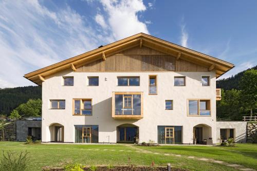 a large white house with a gambrel roof at Mair am Anger-Appartments in Riscone
