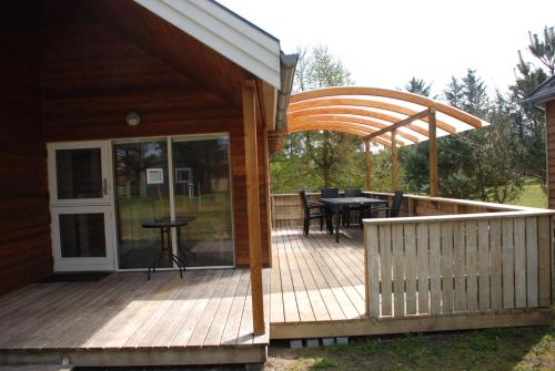 a wooden deck with a pergola and a table at Hytteby – Hanstholm Camping – Thy Feriepark in Hanstholm