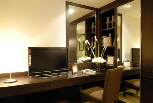 a room with a desk with a television and a chair at The Narathiwas Hotel & Residence Sathorn Bangkok in Bangkok