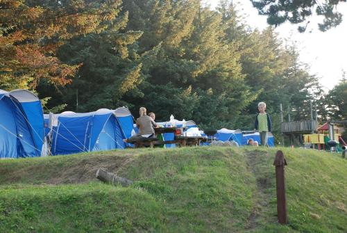 a group of people sitting at a table in front of tents at Hytteby – Hanstholm Camping – Thy Feriepark in Hanstholm