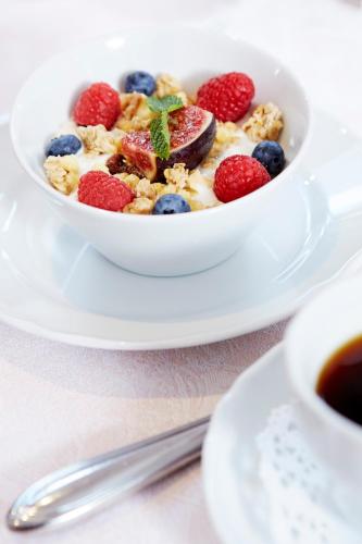 a bowl of cereal with berries and a cup of coffee at Hotel Ziegleder in Rottach-Egern