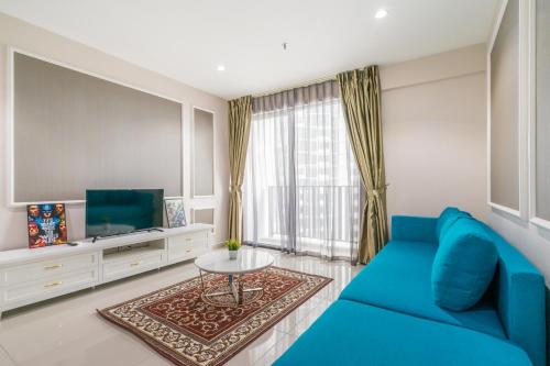 a living room with a blue couch and a tv at HostaHome Suites at I-City, Central Mall in Shah Alam