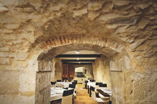 un restaurante con una pared de piedra con mesas y sillas en Hotel Leonor de Aquitania, en Cuenca