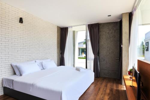sypialnia z białym łóżkiem i ceglaną ścianą w obiekcie Sunnyvale Ranong 1 w mieście Ranong