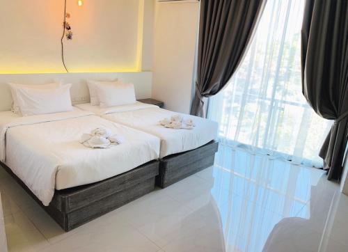 two twin beds in a room with a window at Hotel Chuan Chom The High Resort Saraburi - SHA Plus in Sara Buri