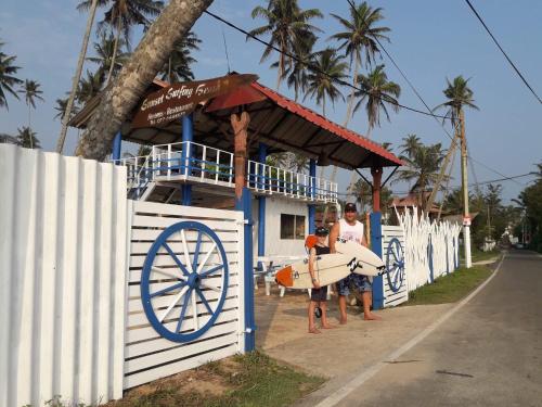 a couple of people with surfboards in front of a building at Sunset Surfing Beach Resort in Matara