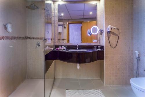 a bathroom with a sink and a shower with a mirror at Al Safir Hotel in Manama