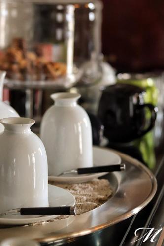a table with two white vases on a plate at Maison Matilda - Luxury Rooms in Treviso