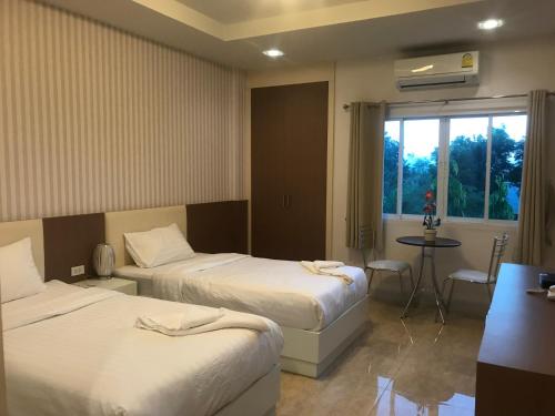 a hotel room with two beds and a table and a window at The Sept Korat in Nakhon Ratchasima