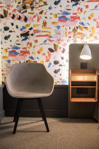 a chair sitting in front of a wall with a butterfly pattern at Hôtel Des Artistes in Lyon