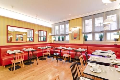 a restaurant with red booths and tables and chairs at Hôtel Des Artistes in Lyon