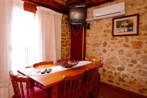 Cette chambre dispose d'une télévision et d'une table en bois avec des chaises. dans l'établissement El Refugi del Maestrat A - Turistrat, à Cervera del Maestre