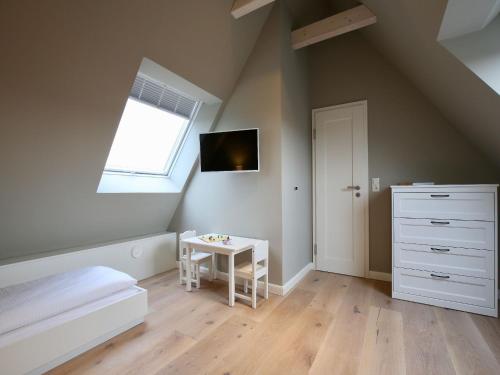 Dormitorio en el ático con cama y mesa pequeña en Charlotte 48 - Wunderschöne Ferienwohnung mit Balkon und Sauna en Wangerooge