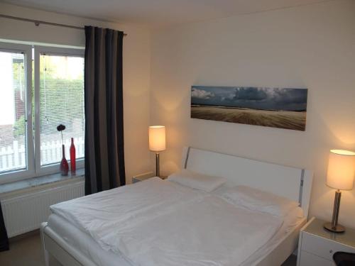 a bedroom with a bed with two lamps and a window at Parkoase in Wangerooge