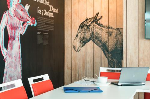 a table with a laptop and a horse on a wall at ibis Styles Carcassonne La Cité in Carcassonne