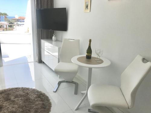 a white room with a table and chairs and a bottle of wine at Style Apartment with Ocean view in Playa de las Americas