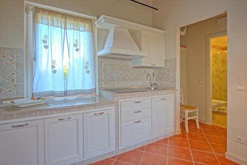 cocina con armarios blancos, fregadero y ventana en Villa Bonriposo by PosarelliVillas, en Legoli