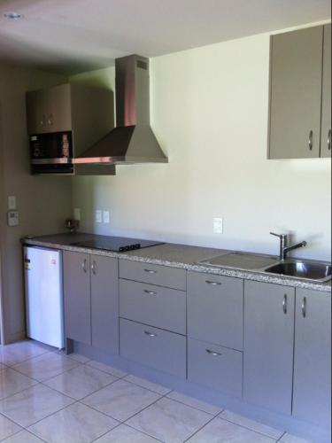 a kitchen with white cabinets and a sink and a stove at The Meadows Villa in Christchurch