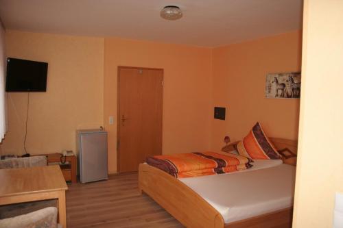 a small bedroom with a bed and a television at Hotel Michaela in Ramstein-Miesenbach