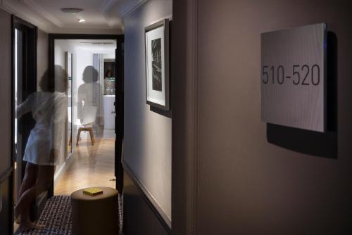 a woman walking down a hallway with a sign on a wall at Hôtel R de Paris - Boutique Hotel in Paris
