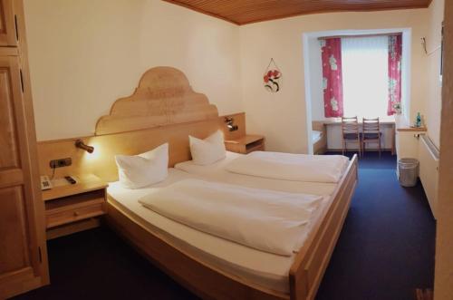 Schlafzimmer mit einem großen Bett mit einem Kopfteil aus Holz in der Unterkunft Gasthof Kern in Idstein