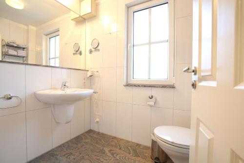 ein weißes Bad mit einem Waschbecken und einem WC in der Unterkunft Villa Vivaldi Whg 5 in Wangerooge