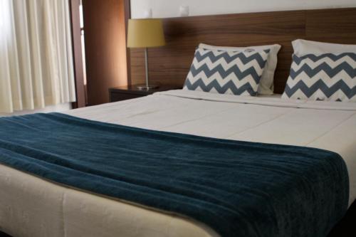 a bedroom with a large bed with a blue blanket at Hotel Santa Cruz in Maputo