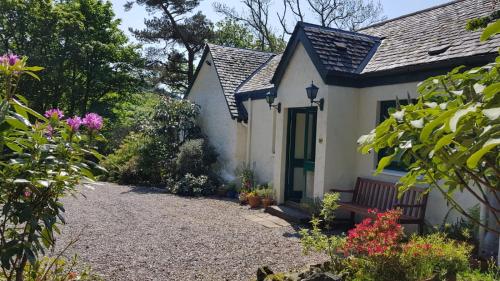 a small white house with a gravel driveway at The Old Cottage in Arduaine
