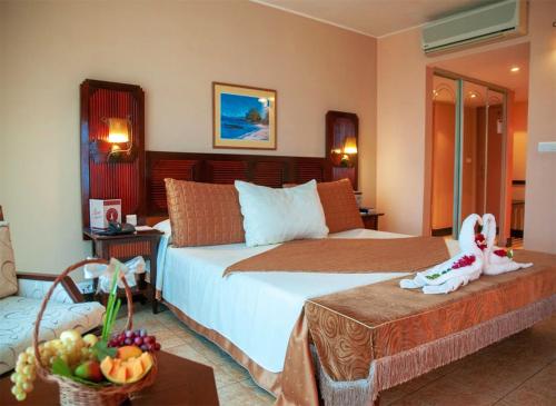 a bedroom with a bed and a table with a bowl of fruit at Le Grand Hôtel Diego in Diego Suarez