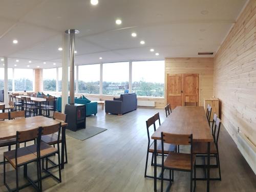 un restaurante con mesas y sillas de madera y ventanas grandes en PAMPA HOSTEL, en Torres del Paine