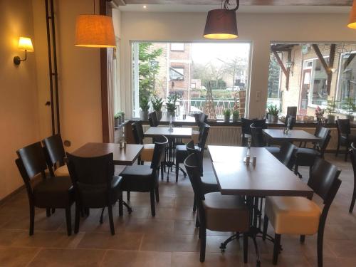 a dining room with tables and chairs and a window at Mimosa Hotel in Valkenburg