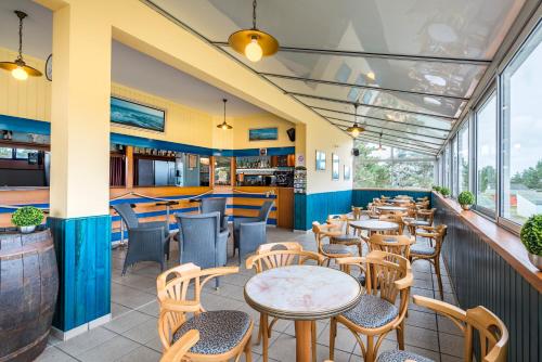 ein Restaurant mit Tischen, Stühlen und Fenstern in der Unterkunft Azureva Hauteville in Hauteville-sur-Mer