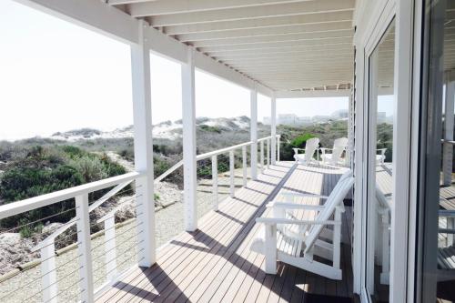 a porch with white chairs and a view of the beach at Thyme & Tide Beach Villa in Yzerfontein