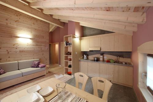 una cucina e un soggiorno con tavolo e divano di Zoncolan Apartments a Sùtrio