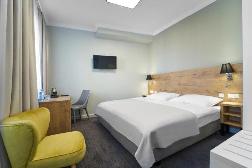 um quarto de hotel com uma cama grande e uma cadeira em Dom Zdrojowy em Jelenia Góra