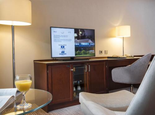 a hotel room with a television and a glass of wine at Maritim Hotel Bonn in Bonn