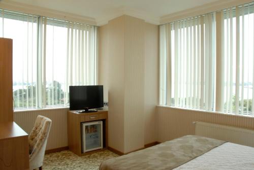 a room with a bed and a tv and windows at Lounge Hotel in Tuzla