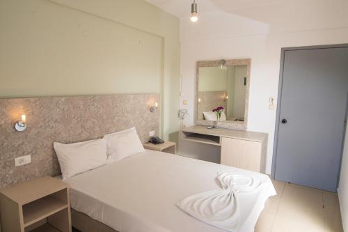 a bedroom with a large white bed and a bathroom at Megim Hotel in Palaiochora