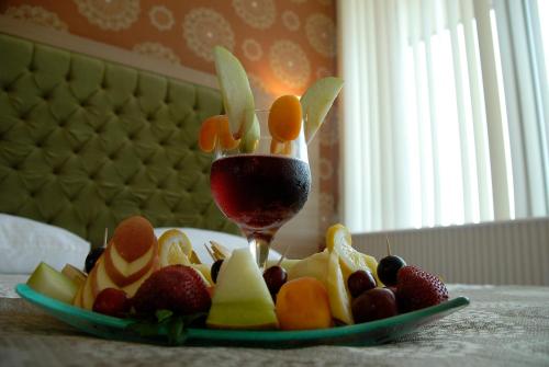 a plate of fruit with a glass of red wine at Lounge Hotel in Tuzla