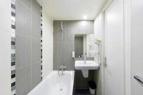a bathroom with a sink and a tub and a toilet at New Hôtel Gare Du Nord in Paris